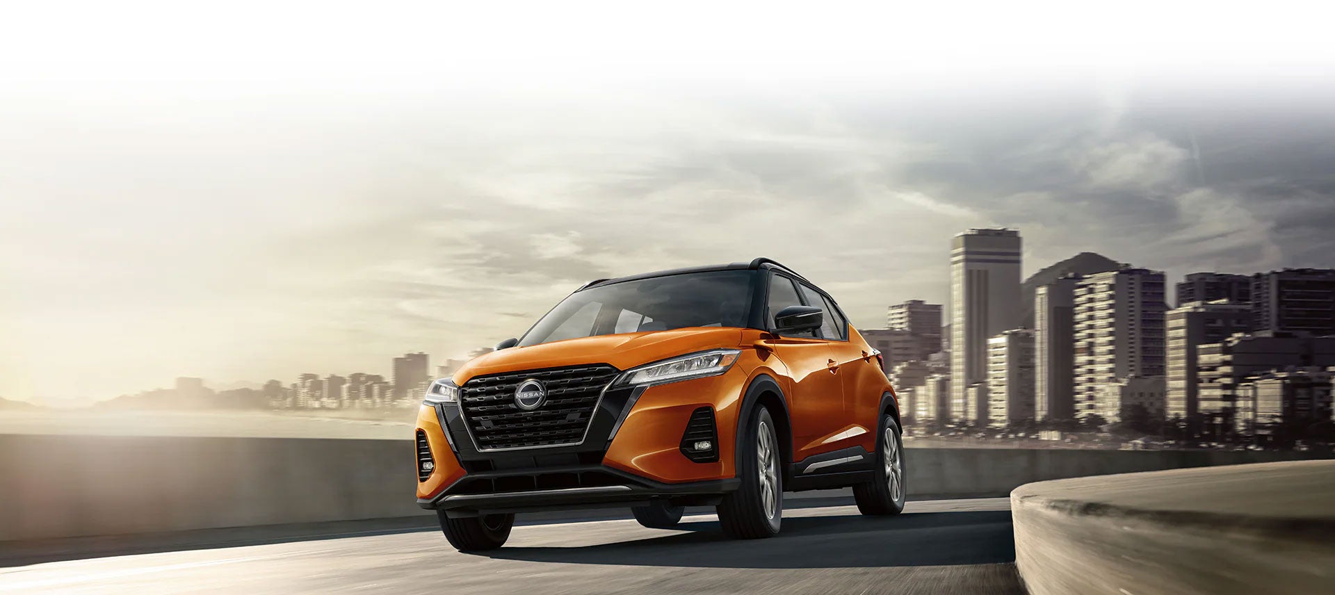 Orange Nissan Kicks driving on a downtown street